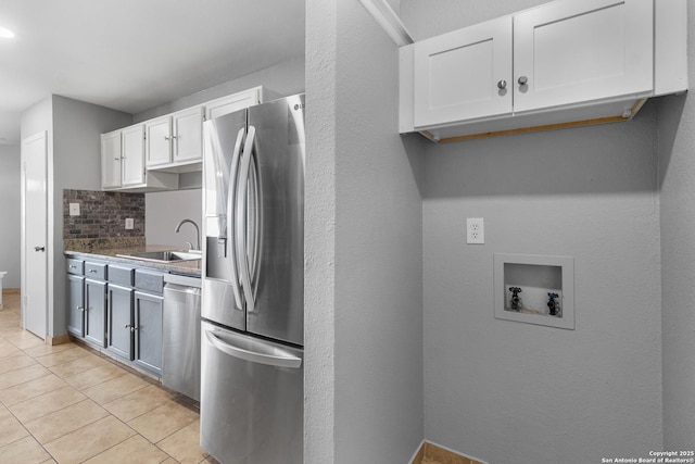 kitchen with light tile patterned floors, white cabinetry, stainless steel appliances, decorative backsplash, and sink