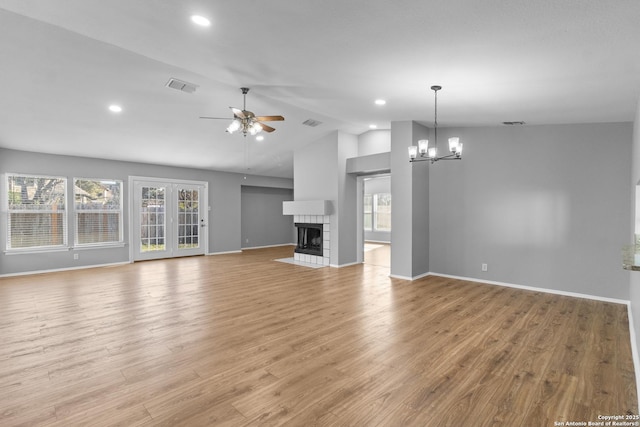 unfurnished living room with lofted ceiling, a healthy amount of sunlight, a fireplace, and light hardwood / wood-style floors