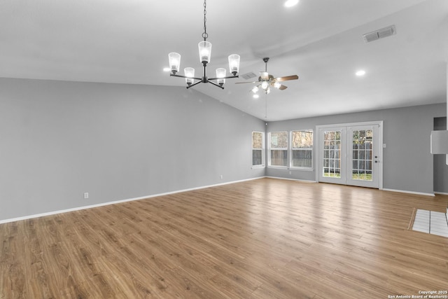 unfurnished living room with ceiling fan with notable chandelier, light hardwood / wood-style flooring, and vaulted ceiling