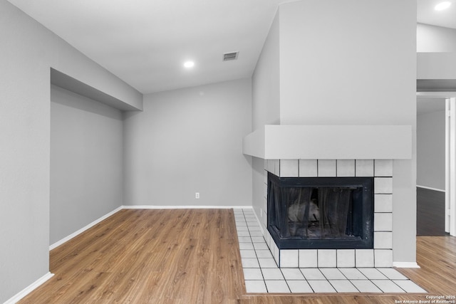 unfurnished living room featuring a tiled fireplace and light hardwood / wood-style floors