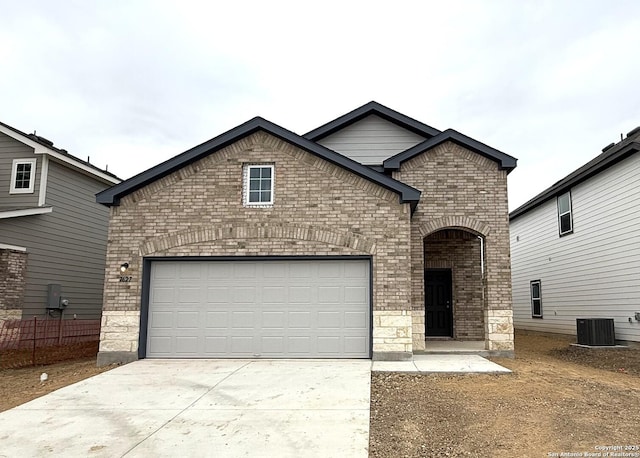 view of front of property featuring a garage and cooling unit