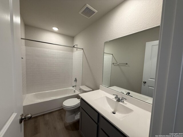 full bathroom featuring tiled shower / bath, vanity, toilet, and hardwood / wood-style floors