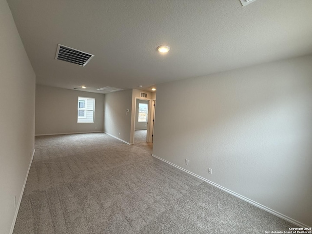 empty room with light carpet and a textured ceiling