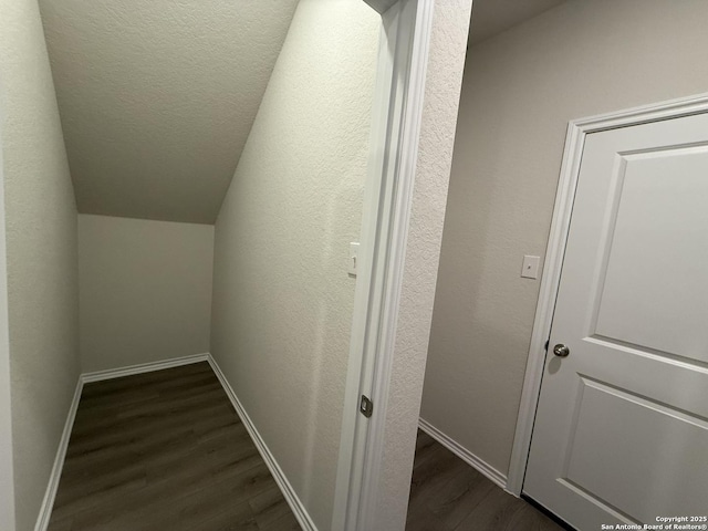 hallway with lofted ceiling, dark hardwood / wood-style floors, and a textured ceiling