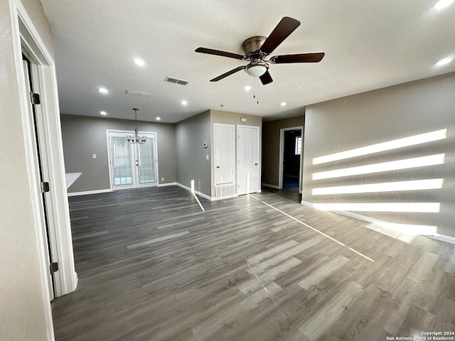 unfurnished living room with french doors, dark hardwood / wood-style floors, and ceiling fan with notable chandelier