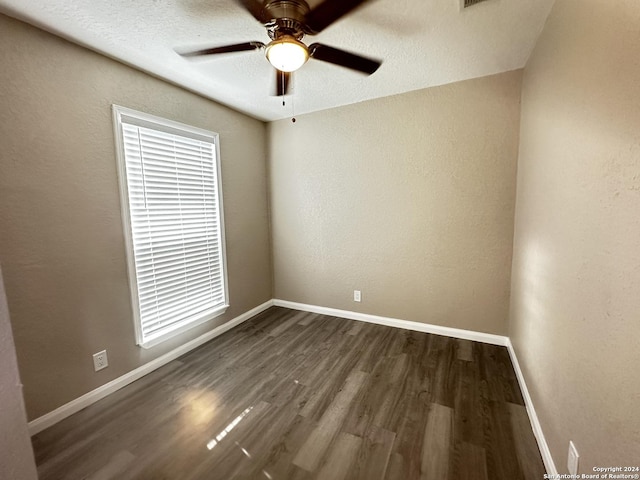 spare room with a textured ceiling, ceiling fan, and dark hardwood / wood-style flooring