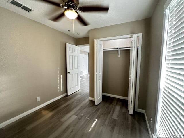 unfurnished bedroom featuring ceiling fan, a textured ceiling, a closet, and dark hardwood / wood-style flooring