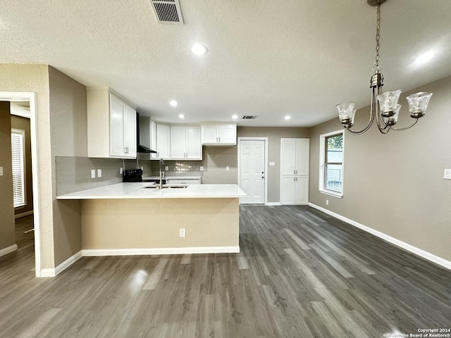 kitchen with kitchen peninsula, backsplash, white cabinetry, and a textured ceiling