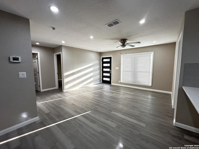 unfurnished living room with ceiling fan, a textured ceiling, and dark hardwood / wood-style flooring