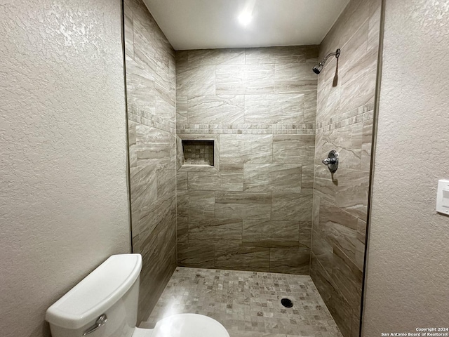 bathroom with toilet and a tile shower