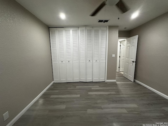 unfurnished bedroom with ceiling fan, dark wood-type flooring, and a closet