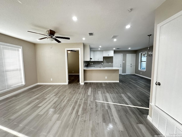 kitchen with white cabinetry, hanging light fixtures, a textured ceiling, dark hardwood / wood-style flooring, and ceiling fan with notable chandelier