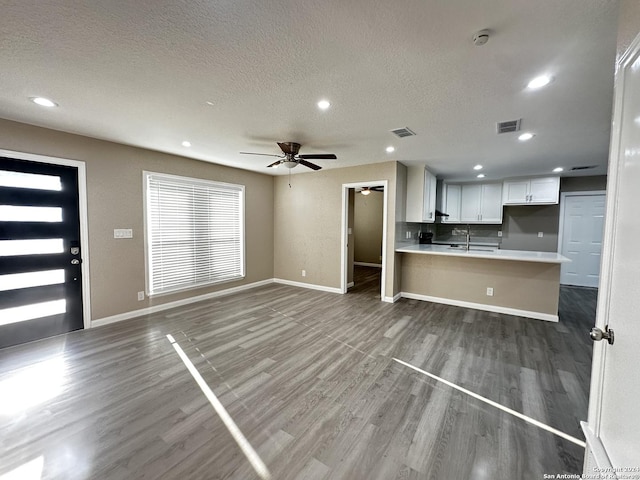 unfurnished living room with a textured ceiling, ceiling fan, and hardwood / wood-style flooring