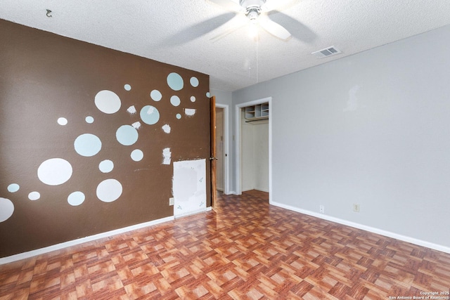 unfurnished room featuring ceiling fan, parquet floors, and a textured ceiling