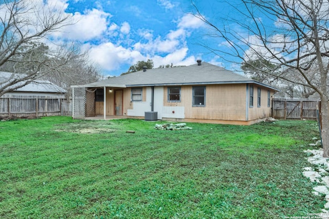 rear view of house with central air condition unit and a yard