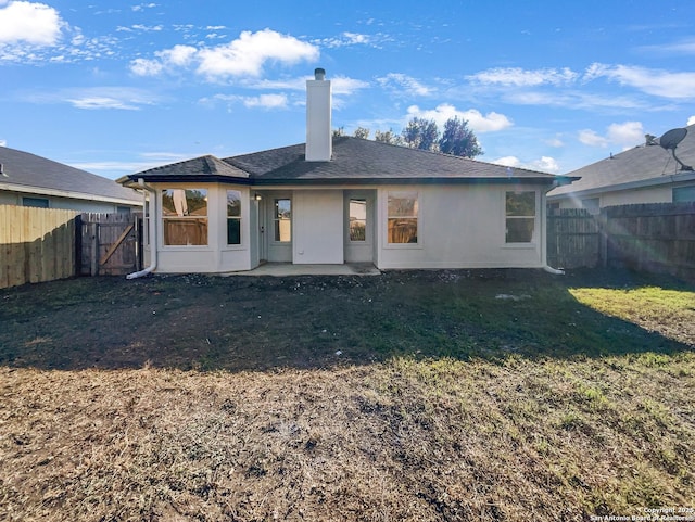 back of house with a patio and a lawn