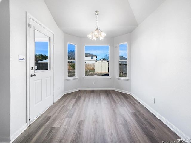 unfurnished dining area with an inviting chandelier, a wealth of natural light, lofted ceiling, and dark hardwood / wood-style flooring