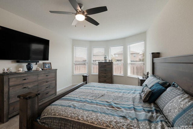 bedroom featuring ceiling fan, hardwood / wood-style floors, and multiple windows