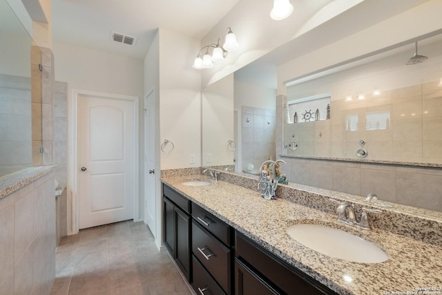 bathroom featuring tile patterned floors, tiled shower, and vanity