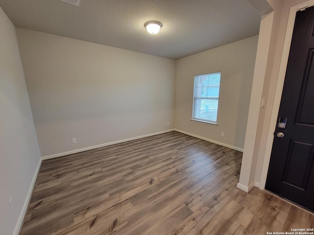 unfurnished room featuring a textured ceiling and hardwood / wood-style floors