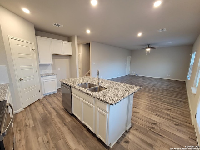 kitchen featuring a kitchen island with sink, dishwasher, light stone countertops, white cabinets, and sink