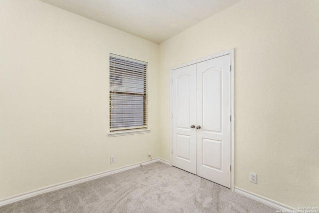 unfurnished bedroom featuring light colored carpet and a closet