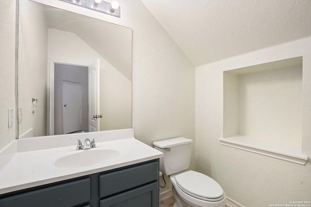 bathroom with vanity, vaulted ceiling, and toilet