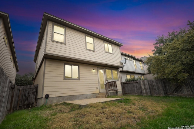 back house at dusk with a lawn