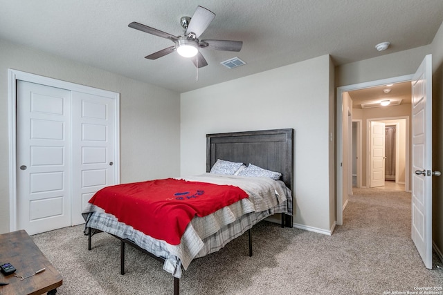 bedroom featuring light carpet, ceiling fan, a closet, and a textured ceiling