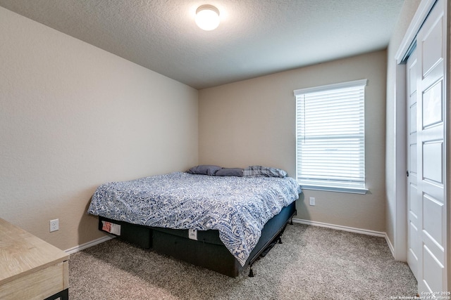 carpeted bedroom featuring a textured ceiling and a closet