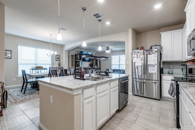 kitchen with white cabinetry, stainless steel appliances, sink, hanging light fixtures, and a kitchen island with sink