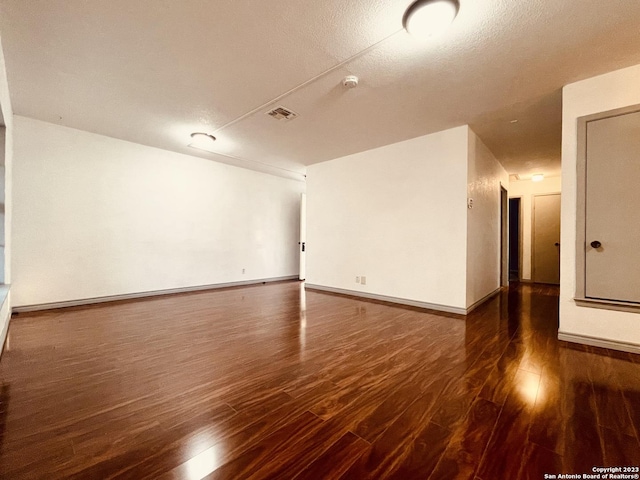 spare room with dark hardwood / wood-style floors and a textured ceiling