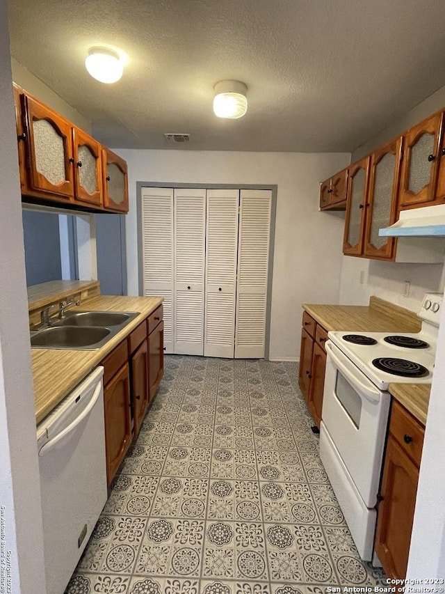 kitchen with sink, white appliances, and a textured ceiling