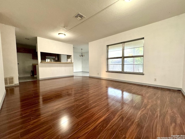 unfurnished living room featuring dark hardwood / wood-style flooring and a textured ceiling