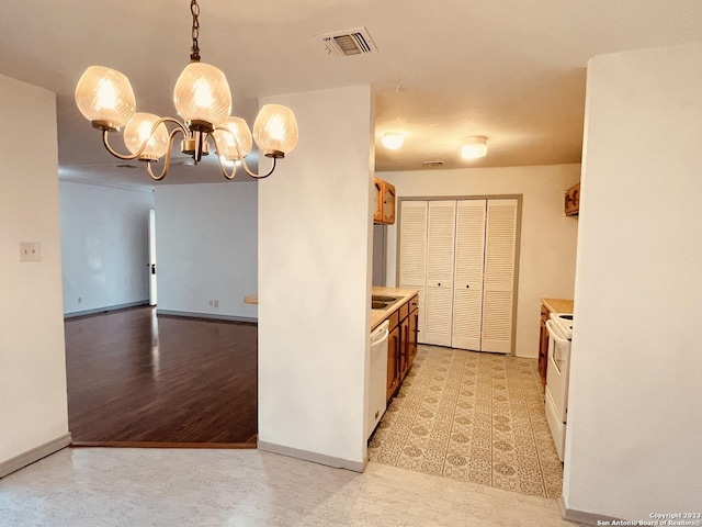 kitchen featuring a chandelier, sink, hanging light fixtures, and white appliances