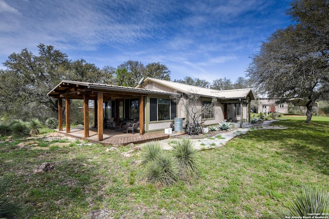 rear view of house featuring a deck and a lawn