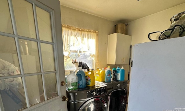 clothes washing area featuring cabinets and washing machine and clothes dryer