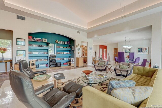 tiled living room with a tray ceiling and built in shelves