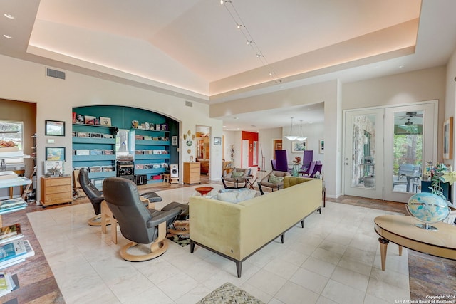 living room featuring lofted ceiling, a raised ceiling, and built in shelves