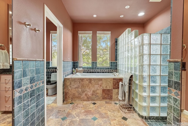 bathroom featuring toilet, tile walls, and shower with separate bathtub