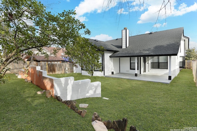 rear view of house with a lawn and a patio