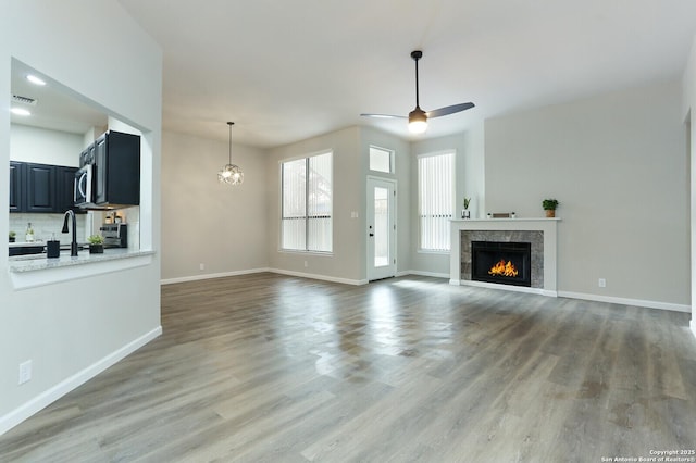 unfurnished living room with ceiling fan with notable chandelier and hardwood / wood-style floors