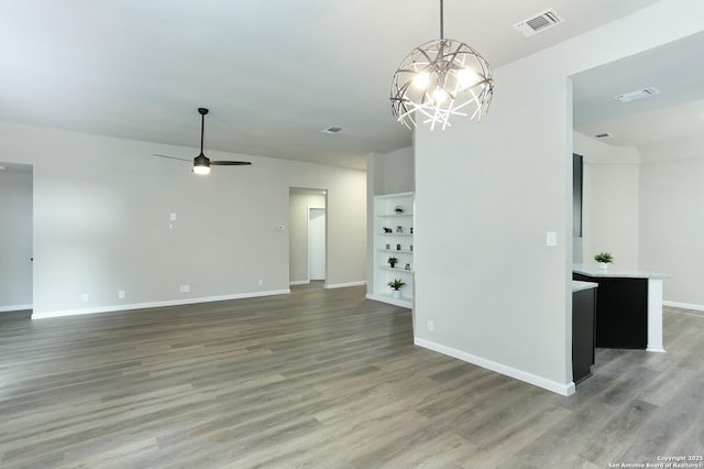 spare room featuring wood-type flooring and ceiling fan with notable chandelier