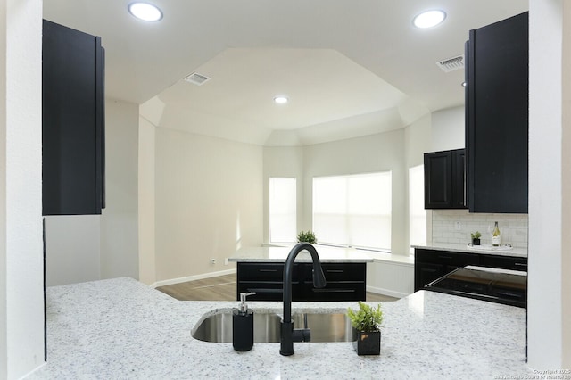 kitchen featuring decorative backsplash, sink, light stone countertops, and light hardwood / wood-style floors