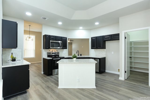 kitchen with pendant lighting, appliances with stainless steel finishes, a center island, and tasteful backsplash