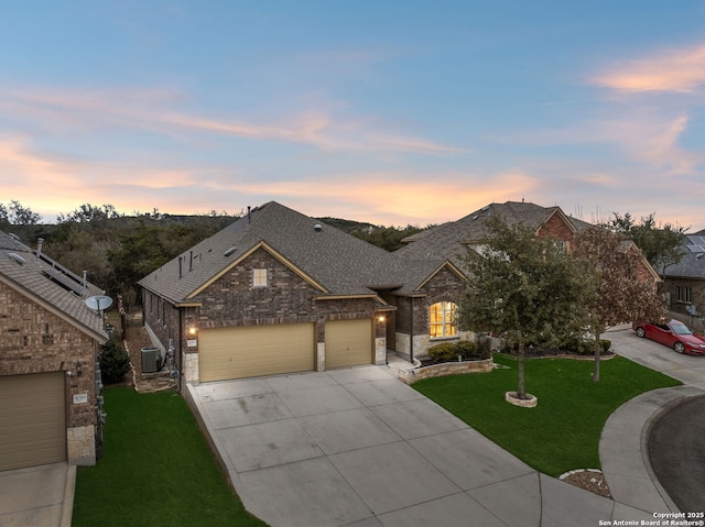 view of front of house featuring a garage, a lawn, and central air condition unit