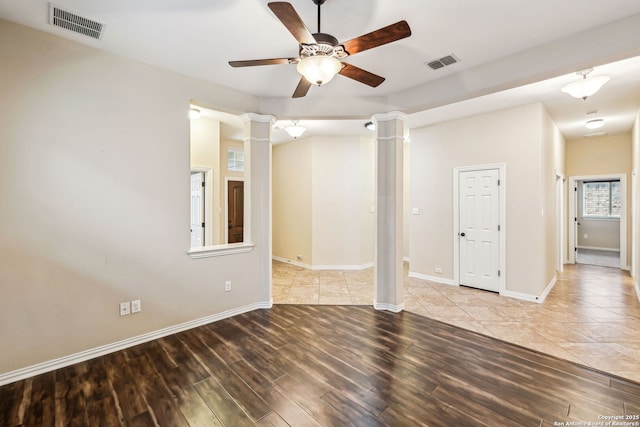 spare room with decorative columns, light hardwood / wood-style floors, and ceiling fan