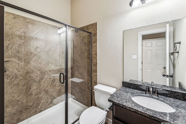 bathroom featuring toilet, vanity, and a shower with shower door