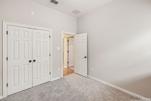 unfurnished bedroom featuring a closet and light colored carpet