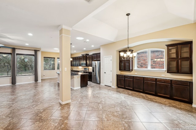 kitchen with an inviting chandelier, dark brown cabinetry, hanging light fixtures, appliances with stainless steel finishes, and decorative columns